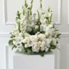 Large all-white urn with layered roses, ruffled blooms and tall spikes, densely