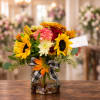 Mixed bouquet with sunflowers and mums in a glass vase with a plaid bow