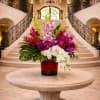 Large mixed orchid arrangement in a red vase on a round table