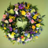 Colorful floral wreath with roses, lilies, and daisies on a green background