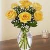 Yellow roses arranged in a clear glass vase with baby's breath