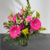 Pink gerberas and roses in a glass vase with yellow filler flowers