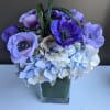 Purple anemones and pale blue hydrangeas in a clear square vase