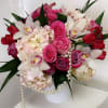 Pink and white floral arrangement in a white vase with pearl strands