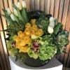 Yellow roses and white tulips in a round black container