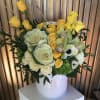 Yellow and white floral arrangement in a white hatbox