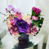 Purple and pink floral arrangement in a dark vase