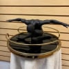 Black sculptural figure on a round mirrored table with gold rails