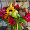 Mixed bouquet with roses, sunflowers, and bright tropical blooms in a glass vase