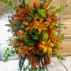 Tall autumn floral arrangement with orange lilies and green blooms