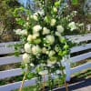 White/green funeral easel featuring mums, roses, snapdragons, Belles of Ireland, daisies, and