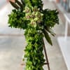 Green floral cross with pale orchids on a stand