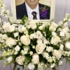 White rose and snapdragon arrangement in front of a framed portrait