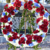 Large floral wreath of red roses, white blooms, and blue flowers on an easel