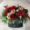 Red roses and mixed blooms arranged in a dark rectangular vase