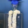 White flower garland on a clear mannequin bust with a blue graduation cap
