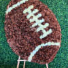 Football-shaped floral display on a wooden easel