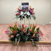 Large tropical floral tribute with white and purple flowers on a stand