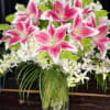 Pink stargazer lilies and white flowers in a glass vase