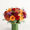 Mixed bouquet of red, orange, and purple flowers in a green vase