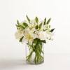 White lilies and roses arranged in a clear glass vase