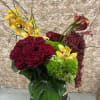 Bouquet of burgundy roses and yellow orchids in a mirrored vase