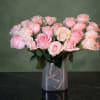 Pink roses arranged in a clear square vase with a ribbon