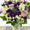 Bouquet of purple and blush roses with white daisies in a glass vase