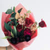 Bouquet of red roses, tulips, and pale pink flowers wrapped in pink paper