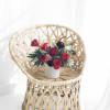 Red rose arrangement in a white vase on a wicker chair