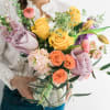 Woman holding a colorful bouquet of roses and tulips in a glass vase