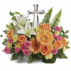 Floral arrangement with white lilies, roses, gerbera daisies, and a silver cross