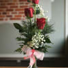 Tall vase arrangement with red roses, baby's breath, and a pink ribbon