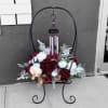 Floral arrangement on a black metal stand with hanging wind chimes