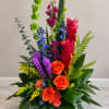 Tall multicolor floral arrangement with orange roses and bright tropical blooms