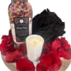 Rose petals with a bath soak jar, candle, and black bath pouf on a tray