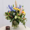 Mixed bouquet in a clear glass vase with a candle beside it