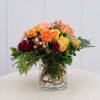 Mixed roses in a clear glass vase with greenery