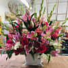 Large pink and red floral arrangement in a white container