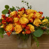 Yellow and orange roses arranged in a clear glass vase