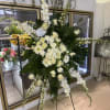 Large white funeral spray on a stand with cascading flowers