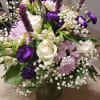 Bouquet of white roses, purple flowers, and pink daisies in a glass vase