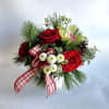 A statement piece with holiday greenery, red roses and orchids including a