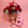 Red rose arrangement in a gift basket with pink cupcakes and a macaron