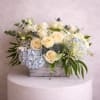 Cream roses and blue hydrangeas arranged in a rustic wooden box