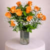 Arrangement of orange roses with white filler flowers in a clear glass cylinder vase