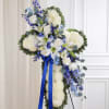 White floral standing cross with blue ribbon and blue flowers