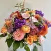Colorful mixed bouquet with orange, pink, and purple flowers in a clear vase
