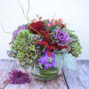 Mixed bouquet with hydrangeas, roses, and purple blooms in a glass vase