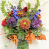 Colorful bouquet with roses, chrysanthemums, and blue flowers in a wrapped vase